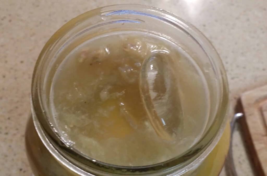 half gallon jar of preserved lemons with glass fermenting weights on top