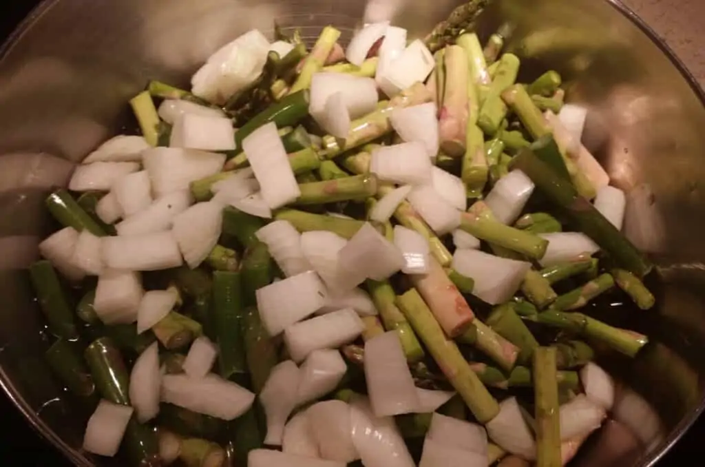 chopped asparagus and onions in chicken stock for asparagus soup