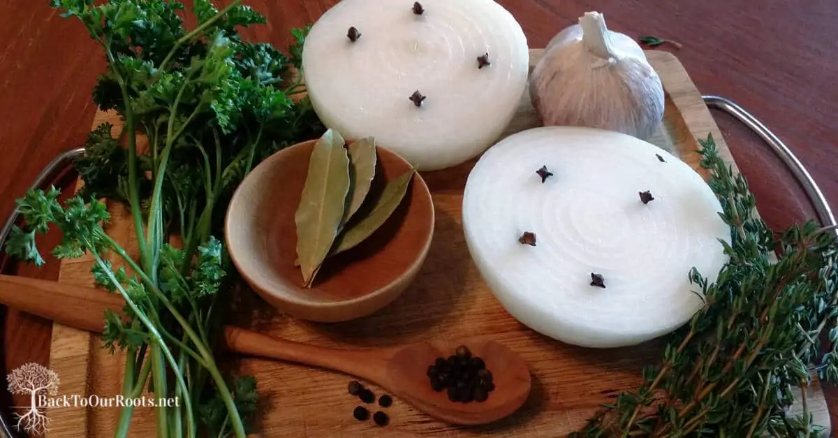 onions, peppercorns, garlic and bay leaves on wooden cutting board