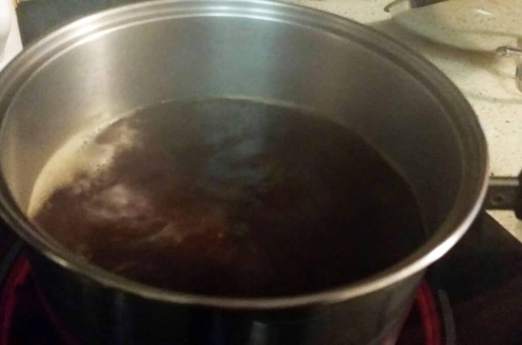 Homemade chicken broth in smaller saucepan boiling down