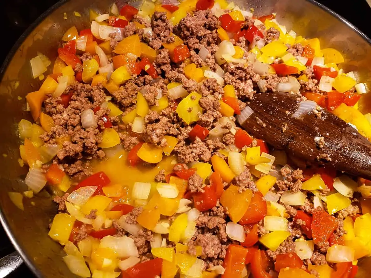 ground beef, chopped bell peppers, onions, and garlic in frying pan
